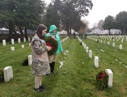 military child lays wreath on a veteran's grave