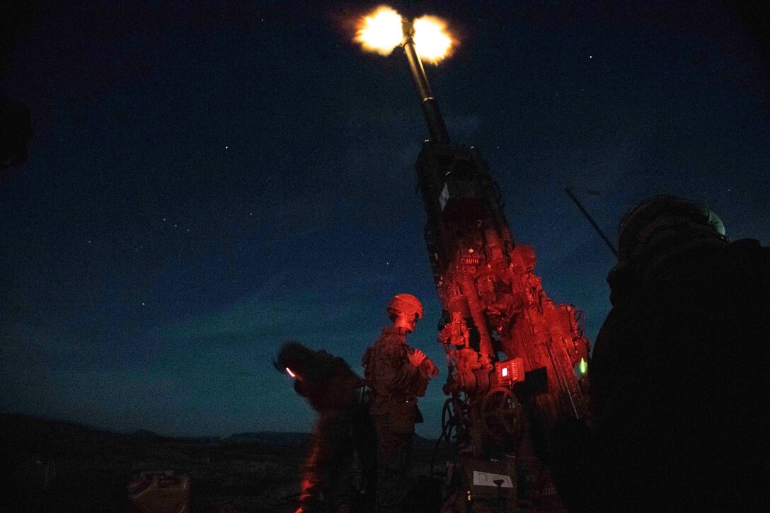 Marines fire an armored vehicle in the dark.