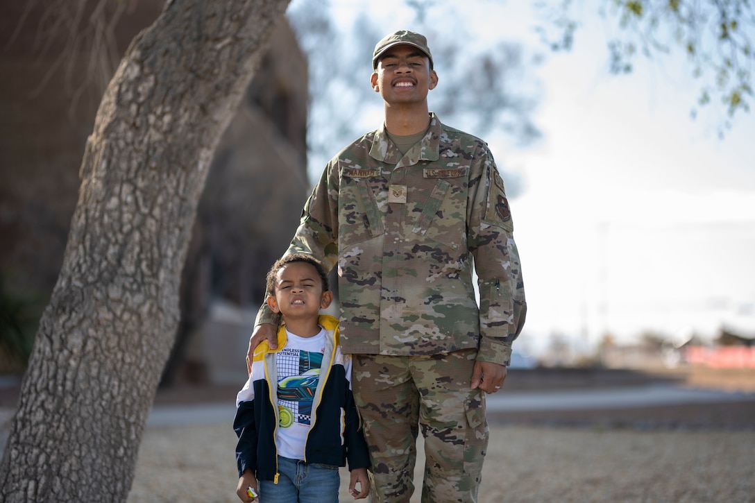 An airman and his son pose for a picture.