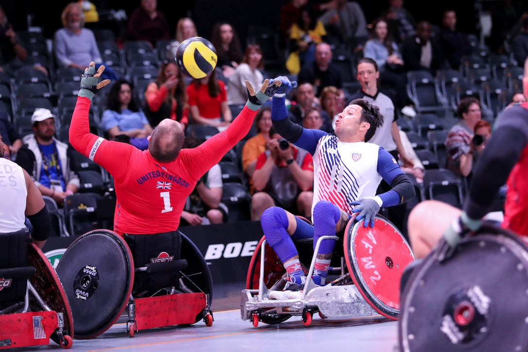 Two men in wheelchairs vie for a ball.