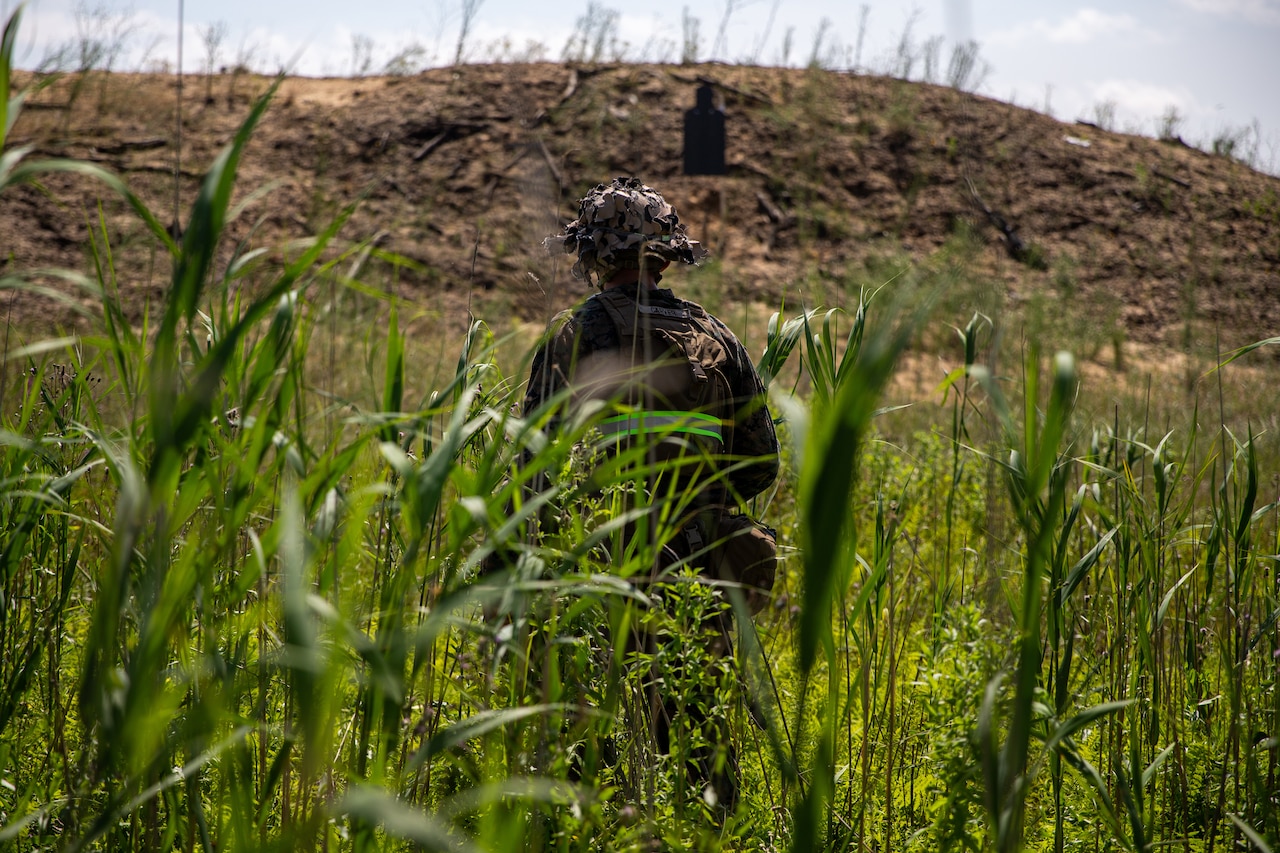 A Marine stands in a field of grass.