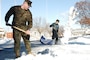 Lance Cpl. William J. Snyder, left, and Mass Communication Specialist 1st Class Darryl Wood clear snow off