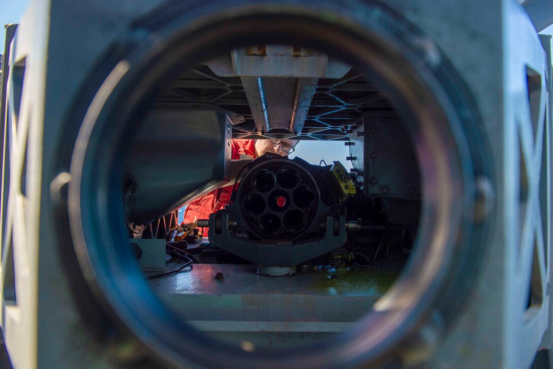 A sailor works inside a piece of equipment.