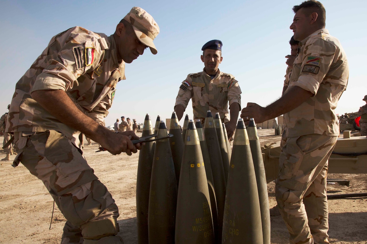 Military personnel handle large explosive rounds.