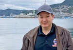 A man poses in front of a harbor.