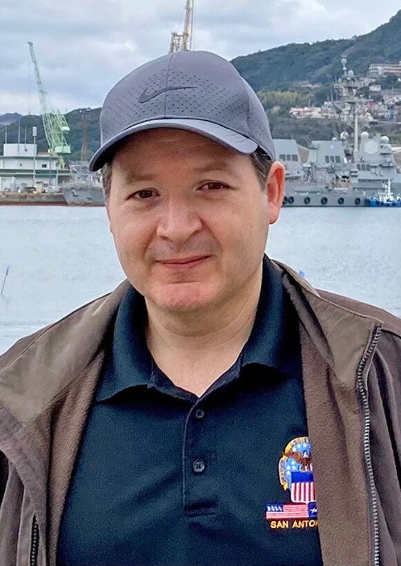 A man poses in front of a harbor.