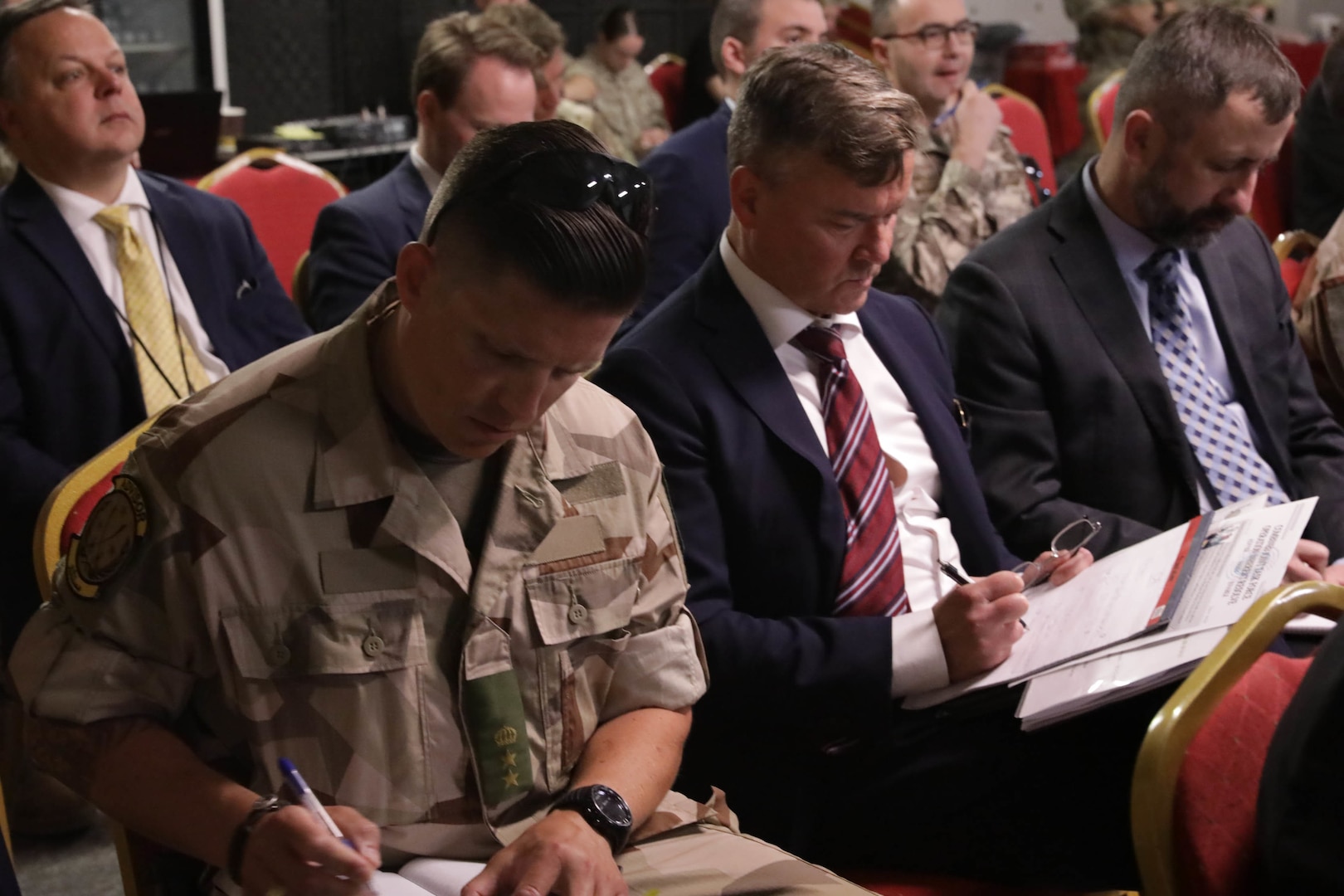 Global Coalition ambassadors and attendees take notes during the Ambassadors Day event at Union III forward operating base in Baghdad, Iraq, April 21, 2022. During the CJTF-OIR-hosted event, representatives from more than 25 Coalition countries discussed the CJTF-OIR mission and broad efforts to tackle enduring regional security and stability challenges. (U.S Army photo by Spc. Nathan Smith)