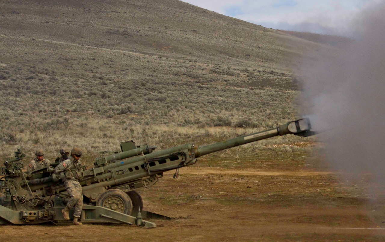 Soldiers fire a large gun.