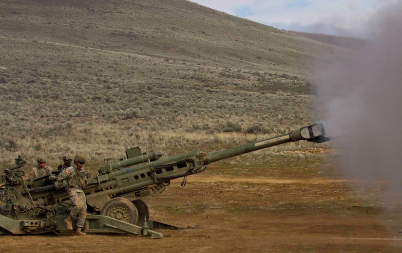 Soldiers fire a large gun.