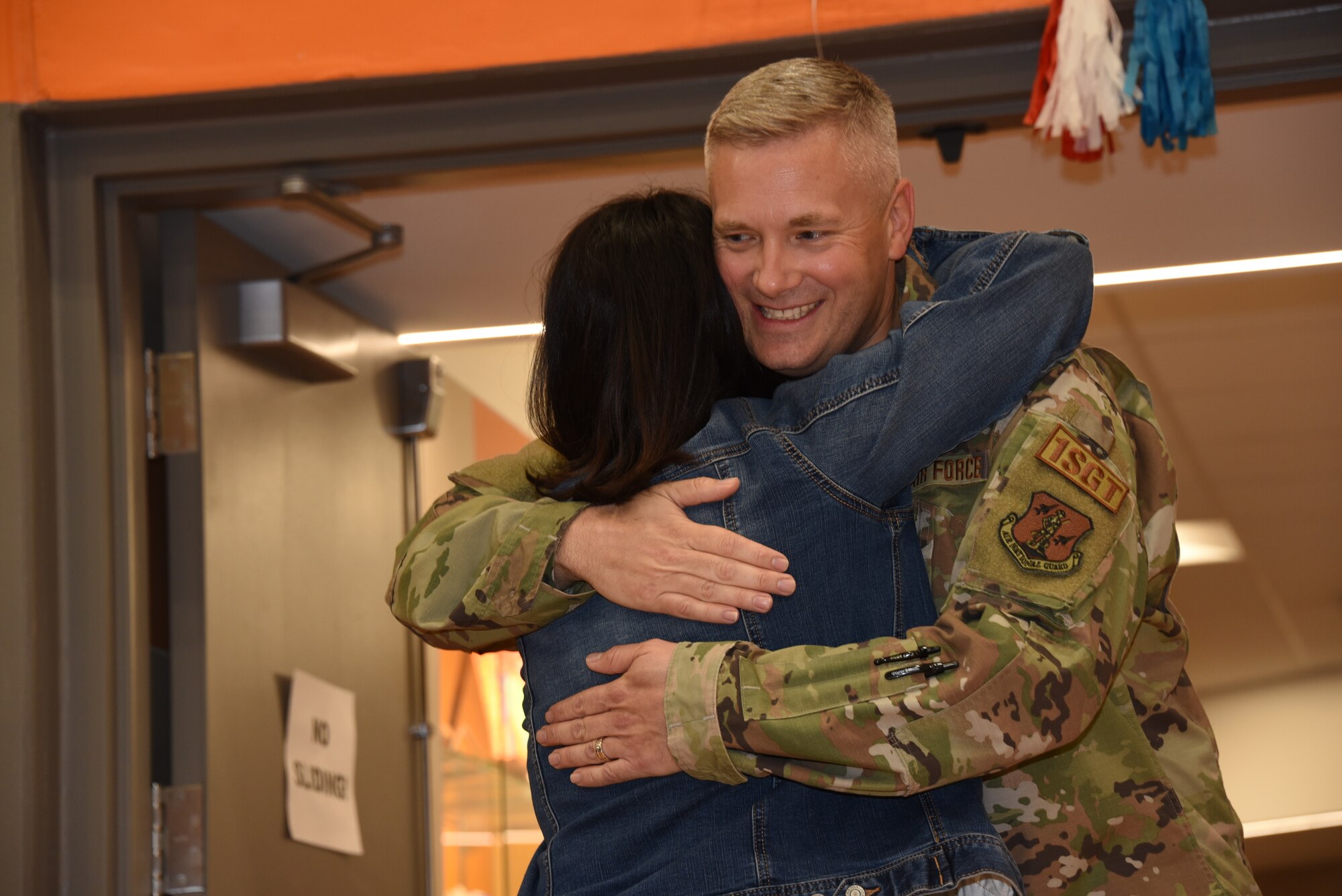 Iowa Air National Guard 1st Sgt. Drew Wagner hugs a teacher at a welcome home event in his honor at the Fort Calhoun Elementary School in Fort Calhoun, Neb., April 21, 2022. Wagner, the school principal, had just returned from a six-month deployment to Southwest Asia.