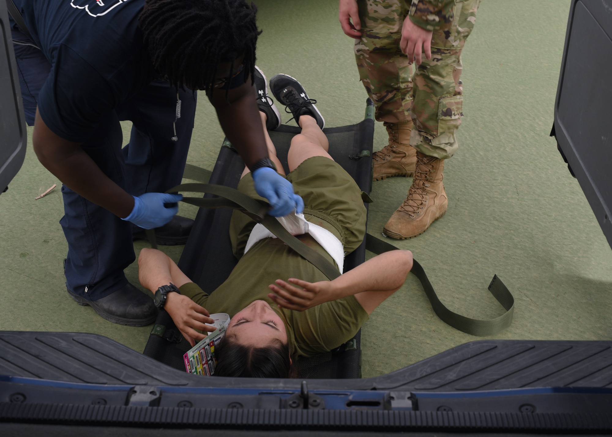 Members assigned to the 17th Civil Engineer Squadron and 17th Medical Group, collaborate to load a pseudo victim into an ambulance during an active shooter exercise at Goodfellow Air Force Base, Texas, April 21, 2022. Active shooter exercises test mission capabilities and reiterate emergency readiness while under pressure of a realistic crisis scenario. (U.S. Air Force photo by Senior Airman Abbey Rieves)