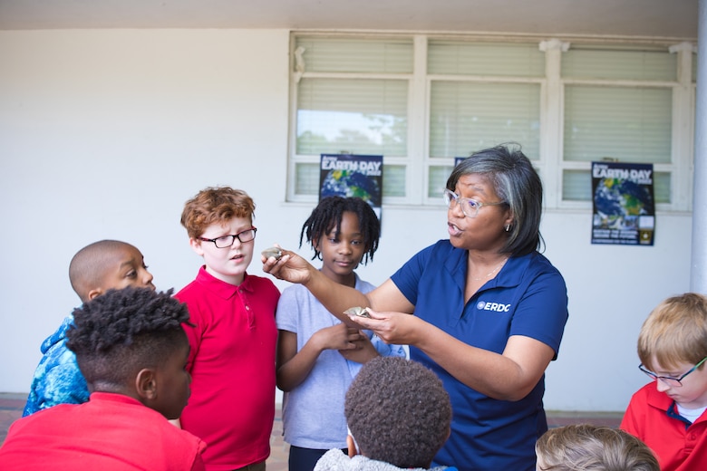 Cynthia Banks (right), U.S. Army Engineer Research and Development Center (ERDC) Installation Operations Command environmental protection specialist, shows fourth grade students from Bowmar Avenue Elementary School in Vicksburg, Miss., different preserved aquatic specimens ― including pallid sturgeon and white shrimp — part of an ERDC outreach effort April 20, 2022, to local schools in celebration of Earth Day. (U.S. Army Corps of Engineers photo)
