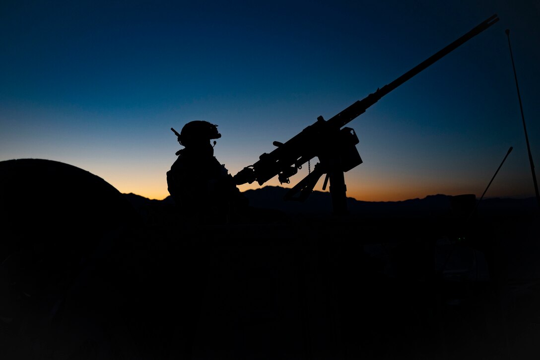 A soldier fires a weapon as shown in silhouette.