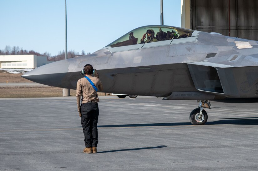 A photo of a crew chief rendering a salute to an F-22 Raptor pilot.