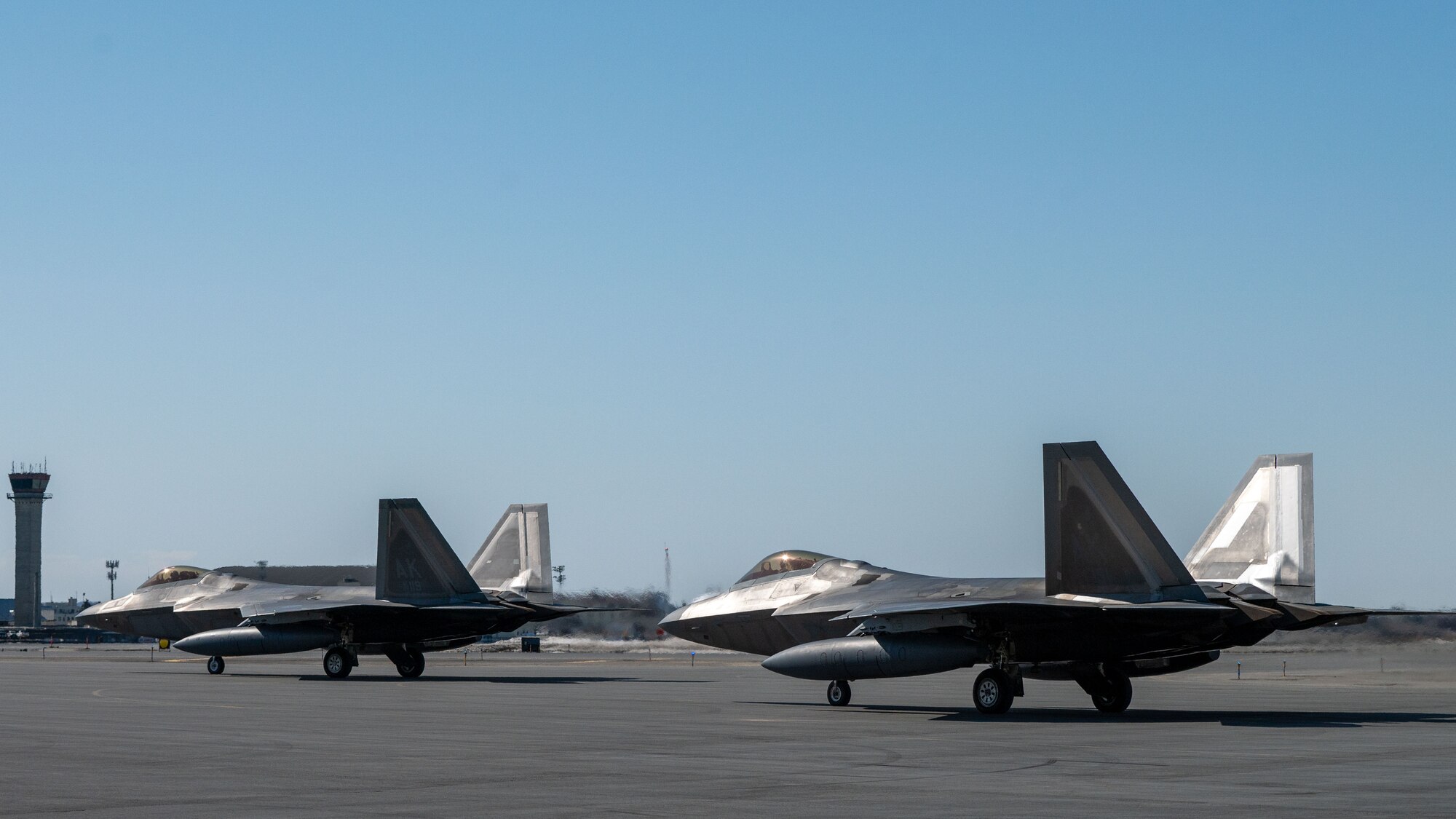 A photo of 2 F-22 Raptors on the flight line.