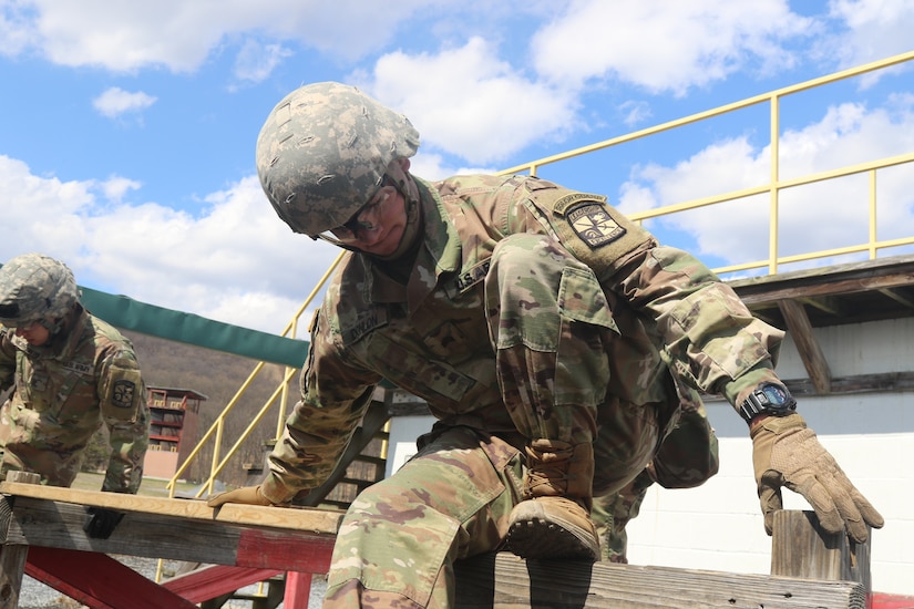 U.S. Army ROTC Cadet Josh Donlon, squad leader with Bucknell University Army ROTC, steadies himself on a wooden beam during a field training exercise at Fort Indiantown Gap, April 8, 2022. Donlan was working with other Soldiers during a group exercise. (U.S. Army National Guard photo by Spc. John Trapani)