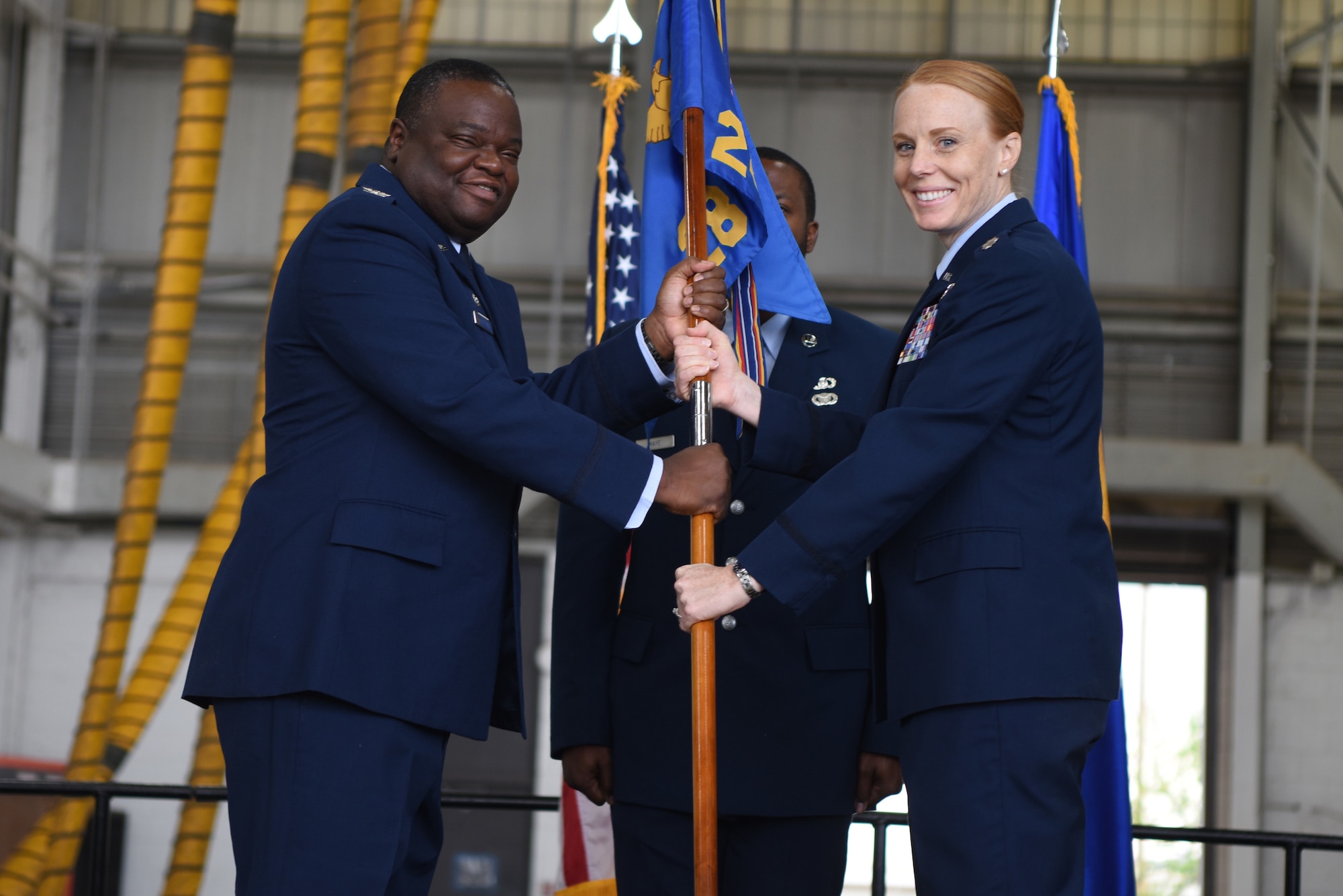 U.S. Air Force Col. John McClung, 7th Operations Group commander, presents the guidon to Lt. Col. Kristen Jenkins, incoming 28th Bomb Squadron commander, during the 28th BS change of command ceremony inside the Three Bay Hangar at Dyess Air Force Base, Texas, April 22, 2022. The 28th BS is the largest bomb squadron in the Air Force and the largest flying squadron in Air Force Global Strike Command. (U.S. Air Force photo by Staff Sgt. Holly Cook)