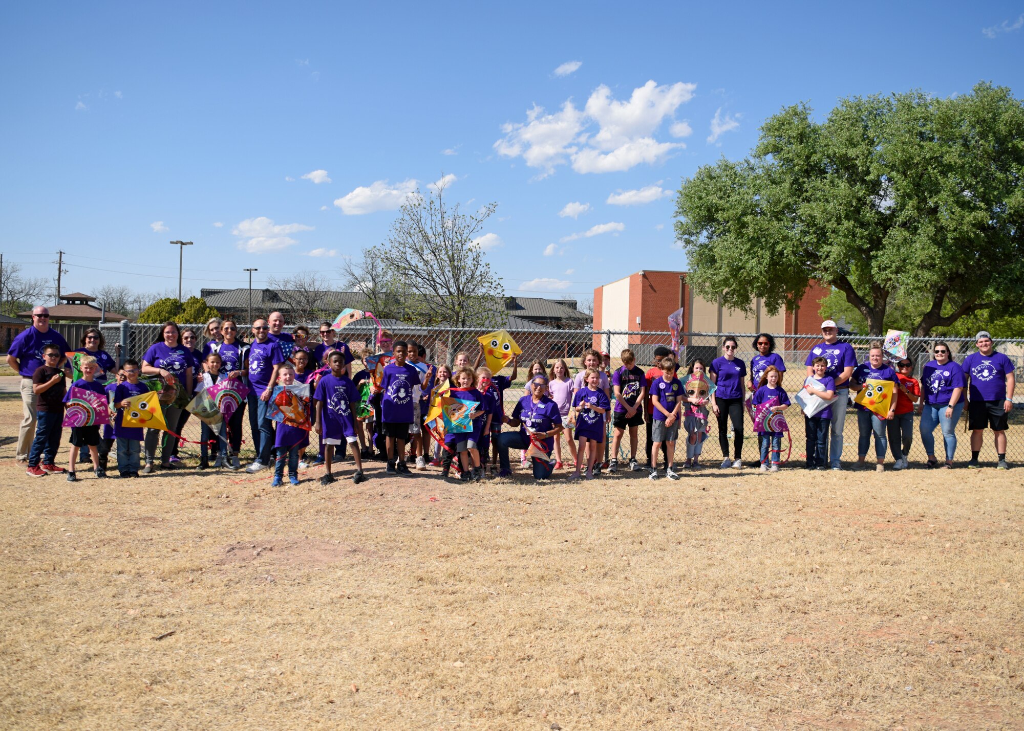 Leadership of the 17th Training Wing, caretakers, parents, students, and children, take a group photo during Purple Up at the School Age Program building, Goodfellow Air Force Base, Texas, April 20, 2022. The wing showed their appreciation to military children by wearing purple for a day and celebrating with various events. (U.S. Air Force photo by Senior Airman Ethan Sherwood)