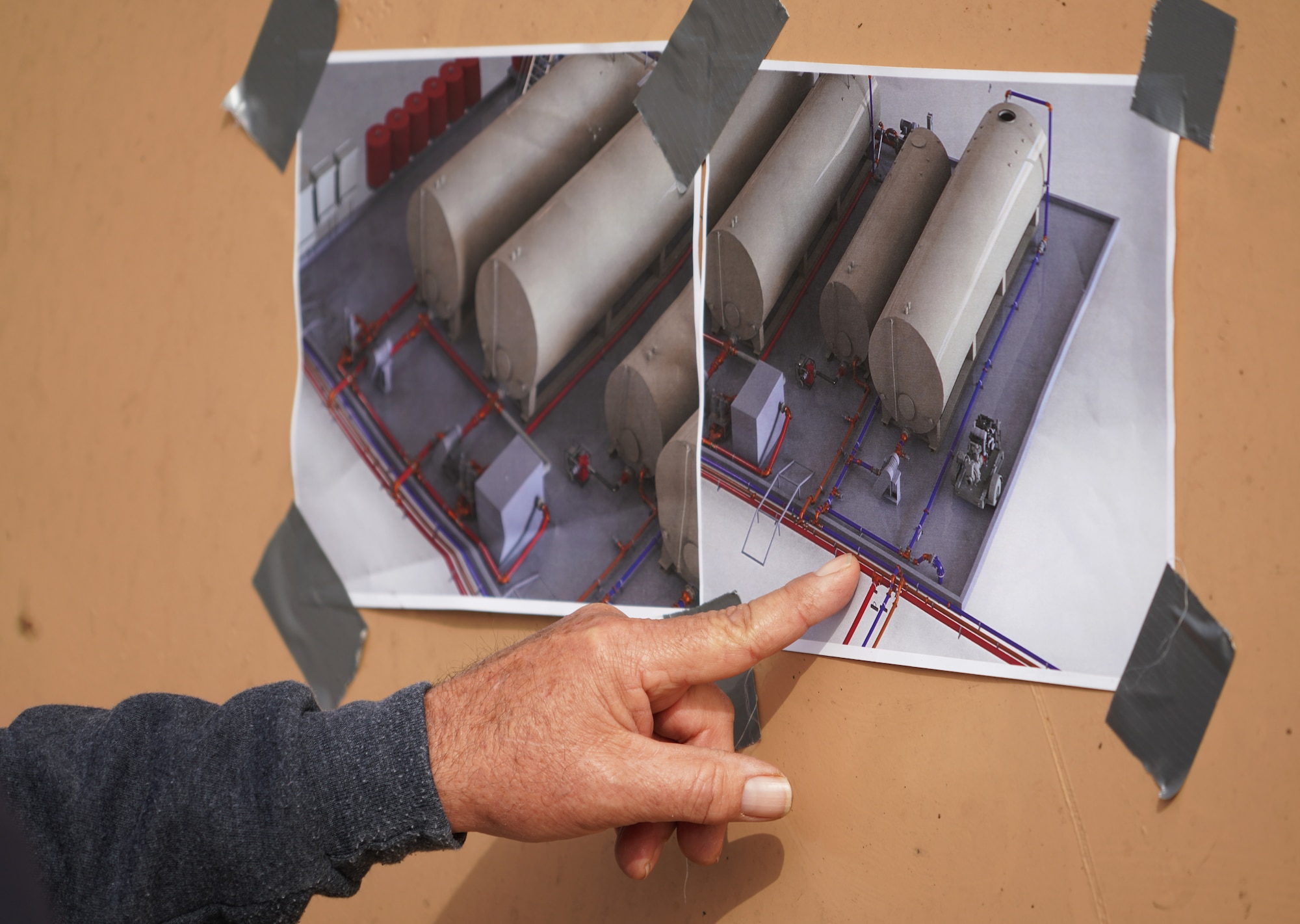 Willie Dayton, a senior field service technician with Perimeter Solutions, reviews photos of the construction site for the 146th Airlift Wing's new MAFFS (Modular Airborne Fire Fighting System) pit with his team at the Channel Islands Air National Guard Station, Port Hueneme, California. March 2, 2022. The new fire-retardant ground tanks have increased the storage capability five-fold from a 10,000-gallon capacity to 50,000 gallons to accommodate more MAFFS aircraft and the U.S. Forest Service's Very Large Air Tankers (VLAT's) with water and fire retardant solution. (U.S. Air National Guard photo by Staff Sgt. Michelle Ulber)