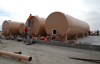 Darrin Hutchison and Tom Miszklevitz, managers with Perimeter Solutions, adjust a nozzle on the 146th Airlift Wing's new Modular Airborne Firefighting System (MAFFS) Pits Ground Tanks, Channel Islands Air National Guard Station, Port Hueneme, California. March 3, 2022. The new fire-retardant ground tanks have increased the storage capability five-fold from a 10,000-gallon capacity to 50,000 gallons to accommodate more MAFFS aircraft and the U.S. Forest Service's Very Large Air Tankers (VLAT's) with water and fire retardant solution. (U.S. Air National Guard photo by Staff Sgt. Michelle Ulber)