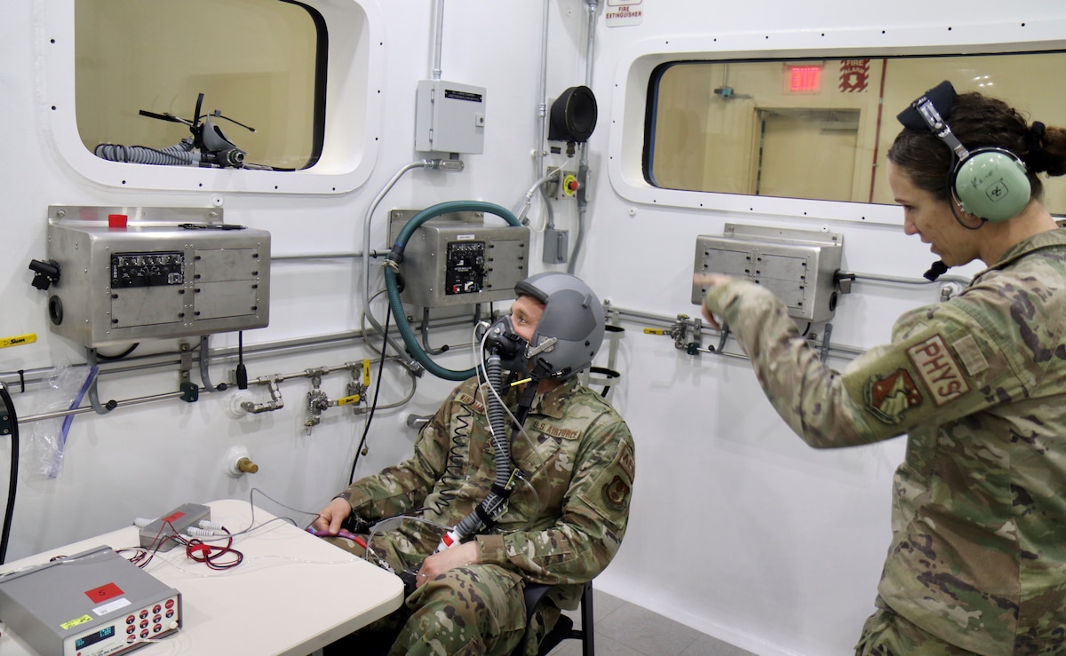 Maj. Sarah Kercher directs Tech. Sgt. Tyler Wineman in preparation for an oxygen system test inside a Research Altitude Chamber at Wright Patterson Air Force Base, Ohio, April 15, 2022. The chamber is one of three at the base that were certified in March for manned research up to 50,000 feet, a benchmark found nowhere else in the Department of Defense. Wineman is an aircrew flight equipment research technician and Kercher is an aerospace physiologist. Both are assigned to the 711th Human Performance Wing, the Air Force Research Laboratory unit that operates the chambers. (U.S. Air Force photo/Jason Schaap)