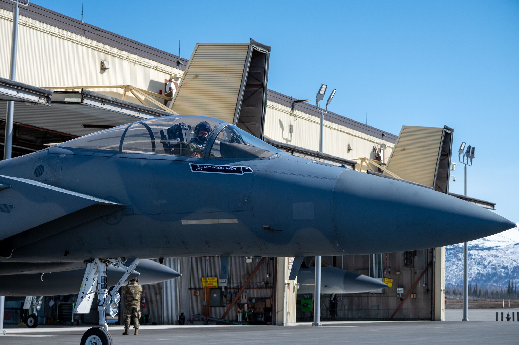 A photo of an F-15 leaving a hangar.