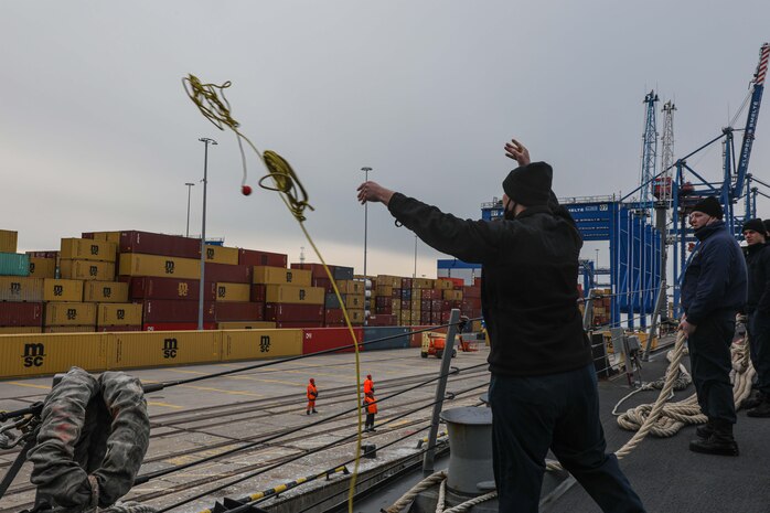 Information Systems Technician 2nd Class Brandon Freppon, left, assigned to Arleigh Burke-class guided-missile destroyer USS Gravely (DDG 107), throws mooring line to the pier while the ships pulls into Klaipeda, Lithuania for a scheduled port visit, April 24, 2022.