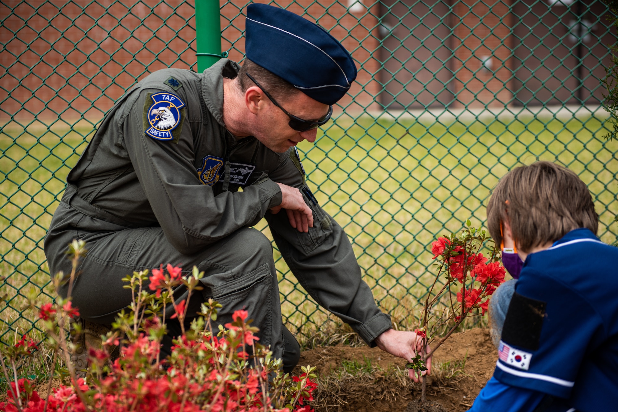 Lt. Col. Jason Rodgers, 7th Air Force Safety Office chief of safety, helps students plant flowers in front of Osan Elementary School, 22 April, 2022 at Osan Air Base, Republic of Korea.