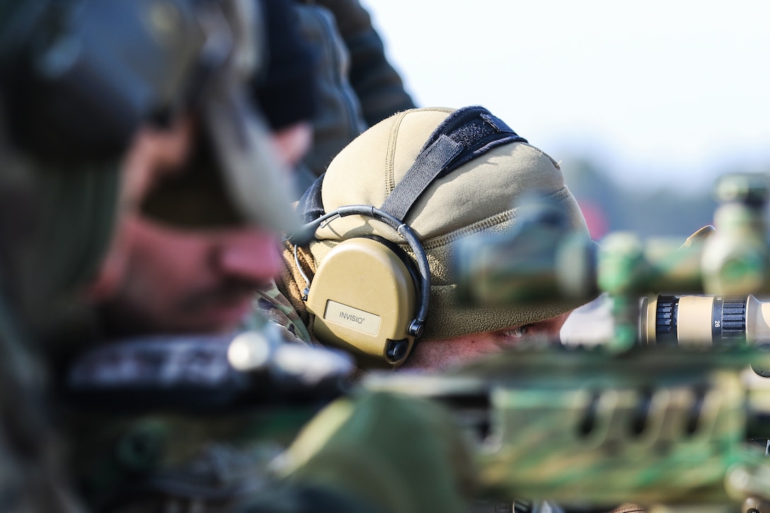 A soldier looks through the lens of a gun scope.