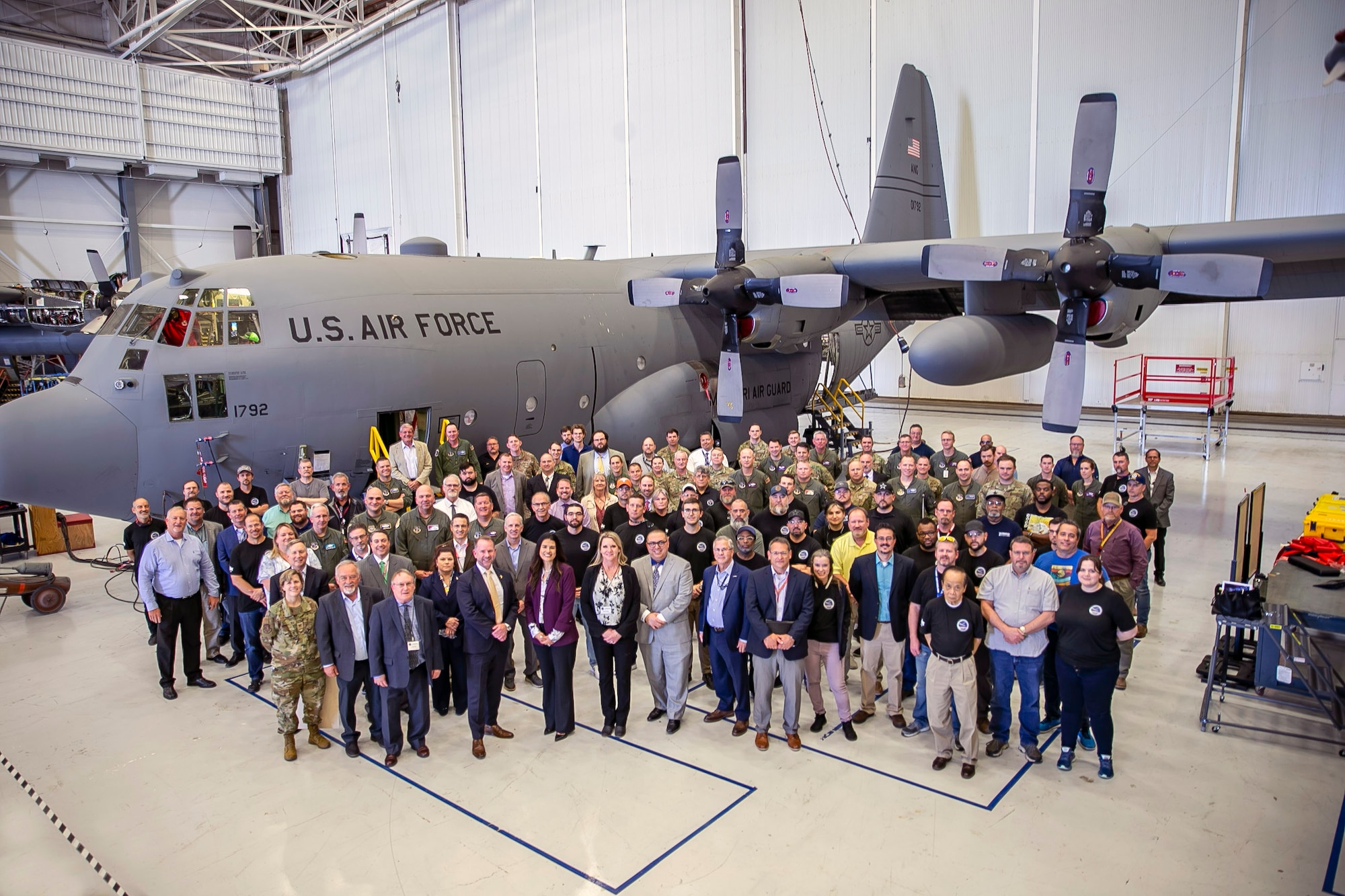 Attendees at a ribbon cutting ceremony to mark the completion of the first Trial Kit Installation (TKI) onto a C-130H from the 139th Airlift Wing. Senior leaders from the Air Force Life Cycle Management Center, and commanders from the 139th, 153rd and 189th Airlift Wings attended the event.  The TKI effort is a key proof-of-concept milestone for the C-130H Avionics Modernization Program (AMP) Increment 2, which modernizes the cockpit while also increasing the reliability and accuracy of the navigation system, thereby improving aircraft sortie rates. (Courtesy photo)