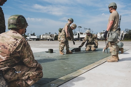 U.S. Air Force Airmen assemble the FRP (Fiber-Reinforced Polymer) to cover a crater on the runway at the Silver Flag exercise site on Tyndall Air Force Base, Florida, March 31, 2022. The primary focus of Silver Flag is to teach Airmen from the civil engineer, force support, and vehicle maintenance squadrons essential skills to complete operations outside of their primary duties. (U.S. Air National Guard photo by Senior Airman Jana Somero)