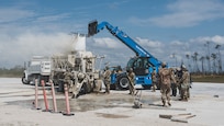 U.S. Air Force Airmen maneuver a telehandler over a cement mixing truck to pour in repair material to patch airfield craters during RADR (Rapid Airfield Damage Repair) operations at the Silver Flag exercise site on Tyndall Air Force Base, Florida, March 31, 2022. The primary focus of Silver Flag is to teach Airmen from the civil engineer, force support, and vehicle maintenance squadrons essential skills to complete operations outside of their primary duties. (U.S. Air National Guard photo by Senior Airman Jana Somero)