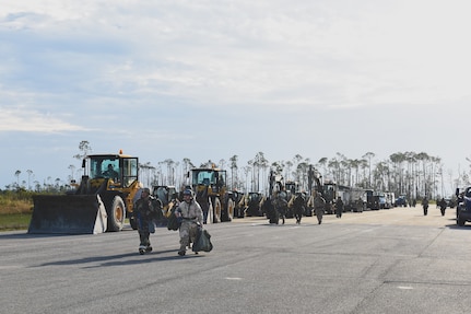 U.S. Air Force Airmen walk to a runway on day one of the student led portion of the Silver Flag exercise at the Silver Flag exercise site, Tyndall Air Force Base, Florida, March 31, 2022. The primary focus of Silver Flag is to teach Airmen from the civil engineer, force support, and vehicle maintenance squadrons essential skills to complete operations outside of their primary duties. (U.S. Air National Guard photo by Senior Airman Jana Somero)