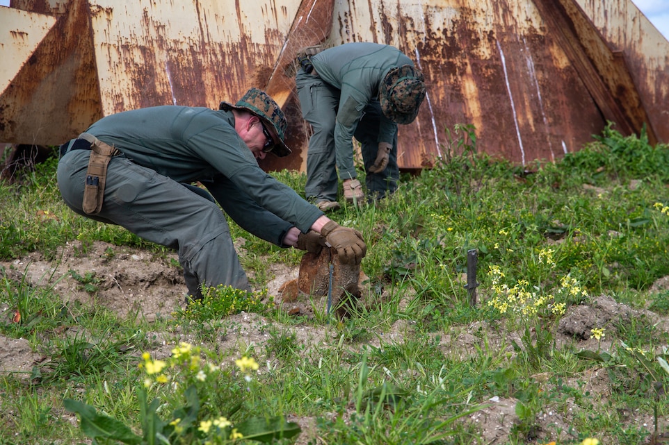 U.S. Marine Corps Staff Sgt. Leon Nevins (left), an explosive ordnance technician assigned to Marine Wing Support Squadron 271, 2nd Marine Aircraft Wing, pulls debris out of the ground at Bombing Target 11 (BT-11), North Carolina, April 13, 2022. Marines swept target areas to locate, identify, and remove all ordnance that no longer possess explosive hazards from BT-11 and handed over certified materials to Cherry Targets for proper disposal. (U.S. Marine Corps photo by Lance Cpl. Lauralle Walker)