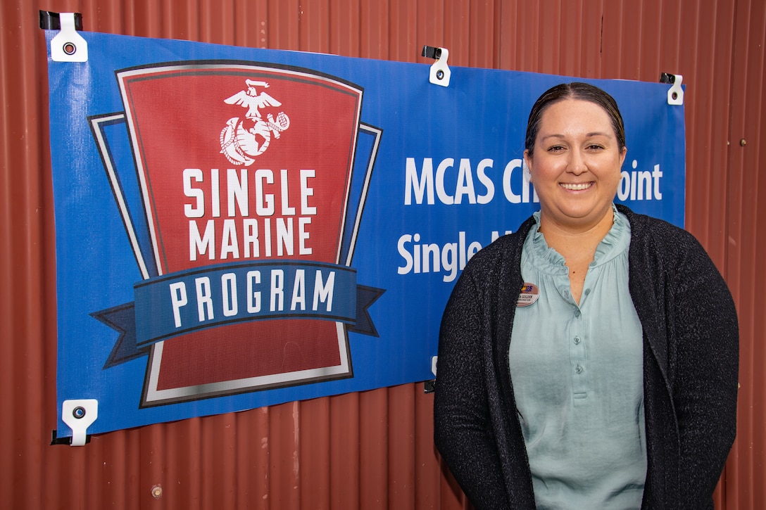 Vanessa Golden stands outside her office alongside the Single Marine Program banner at Marine Corps Air Station (MCAS) Cherry Point, North Carolina, April 7, 2022. The primary mission and focus of the SMP is to enhance the quality of life and improve the morale and well-being of all single and unaccompanied Service Members stationed at MCAS Cherry Point. (U.S. Marine Corps photo by Lance Cpl. Jacob Bertram)