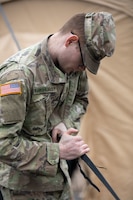a Soldier helps raise a tent