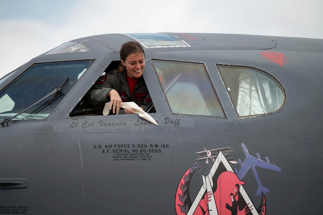 An airman pulls tape off a plane to reveal a name.