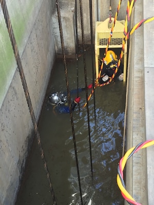 diver working in a narrow space surrounded by concrete and wires