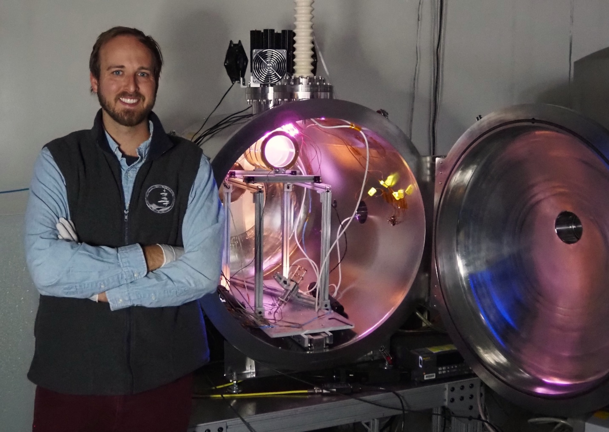 Dr. Miles Bengtson, an Air Force Research Laboratory postdoctoral scientist, stands next to the vacuum chamber in the AFRL Space Vehicles Directorate’s Spacecraft Charging and Instrument Calibration Lab at Kirtland Air Force Base, N.M. in which a multi-energy electron source is developed and tested.