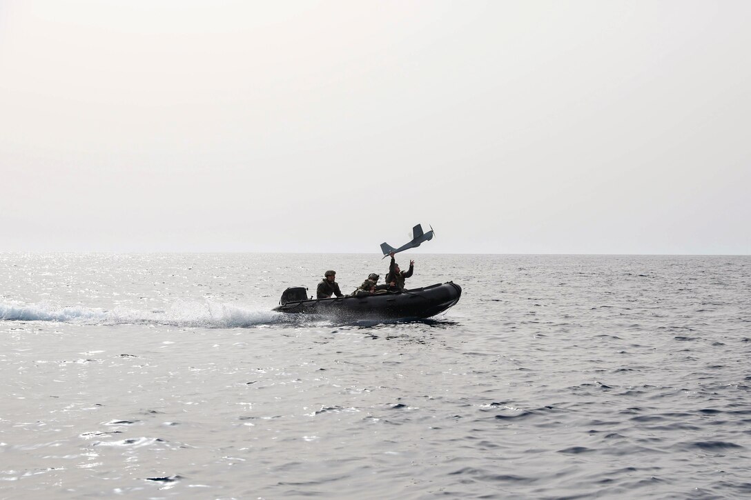 Marines in a small boat operate a small unmanned aircraft system.