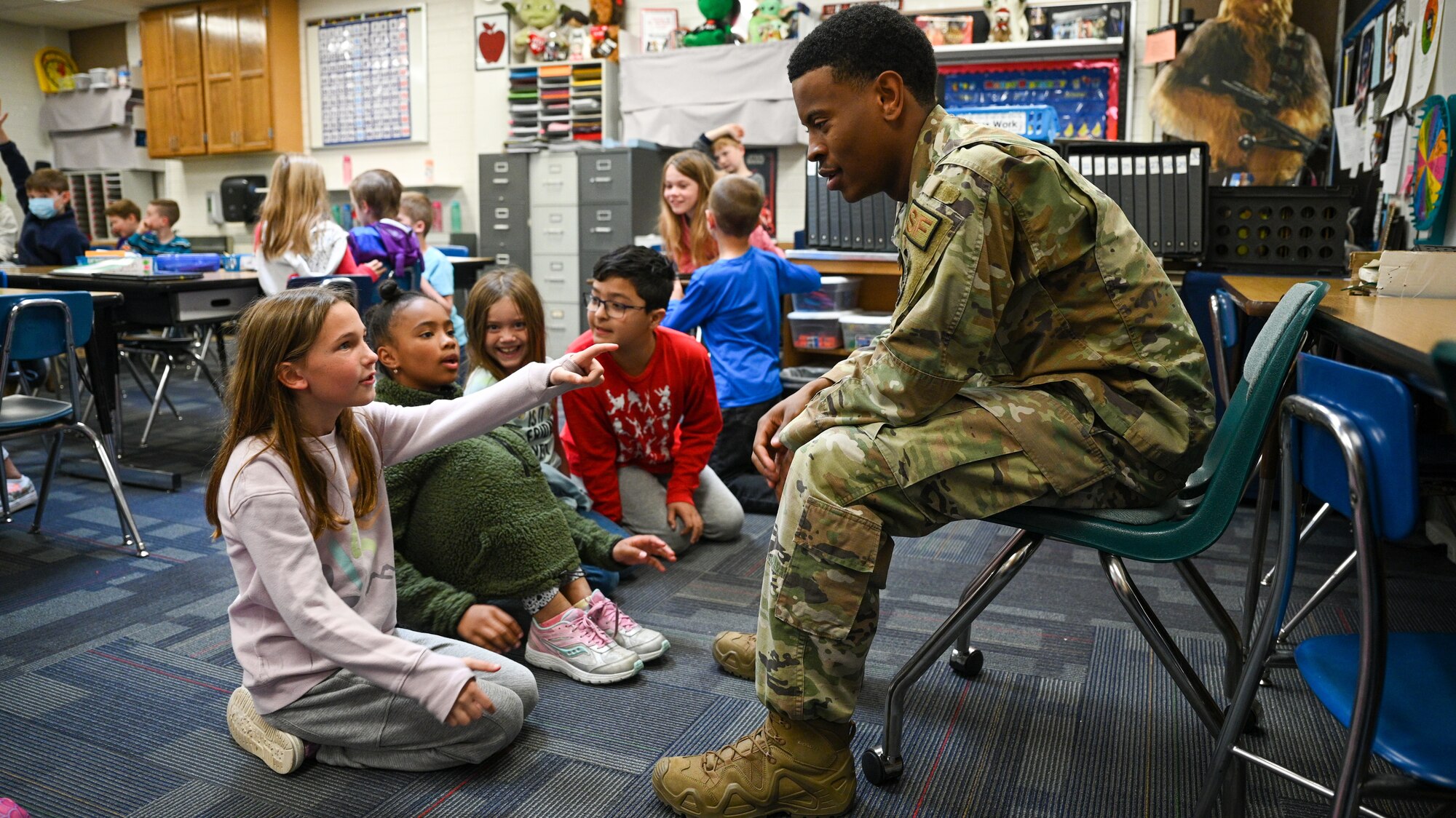 Senior Airman Hason Kimble, 75th Security Forces Squadron, speaks with students at Hill Field Elementary School during a Heroes Reading event, April 22, 2022. The Heroes Reading program is an annual event conducted by the Hill AFB School Liaison office in partnership with local elementary schools. The event is held each spring in conjuction with April's Month of the Military Child. This year marks a relaunch of the program after a hiatus due to the COVID-19 pandemic. During the month, Airmen volunteers will visit three schools and read to more than 1,400 students. (U.S. Air Force photo by R. Nial Bradshaw)