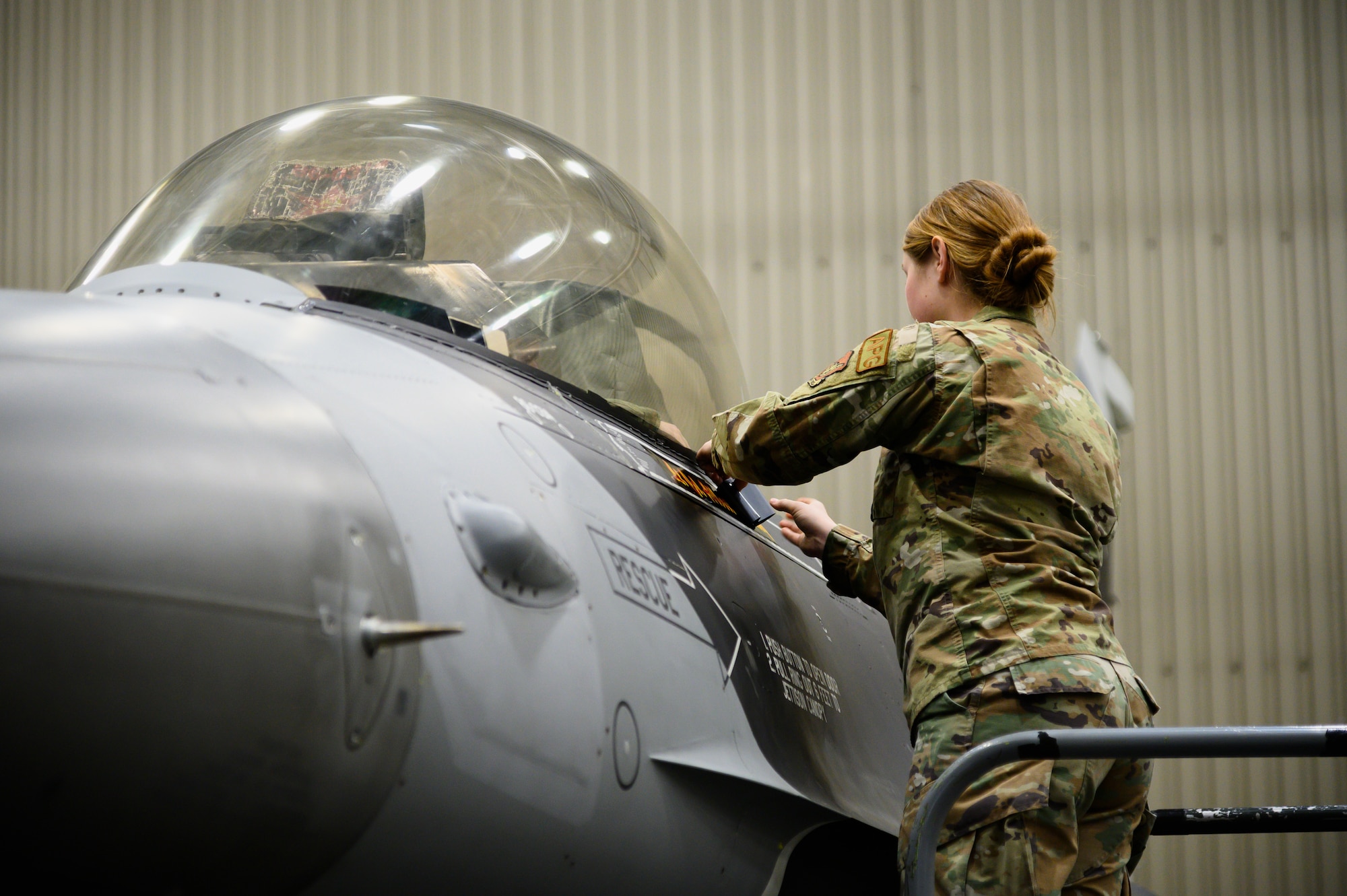 U.S. Air Force Staff Sgt. Timarra Roth, an 18th Aggressor Squadron crew chief, unveils Lt. Col. Albert Roper’s, the incoming 18th AGRS commander, name on an F-16 Fighting Falcon during an 18th AGRS change of command ceremony on Eielson Air Force Base, Alaska, April 22, 2022.