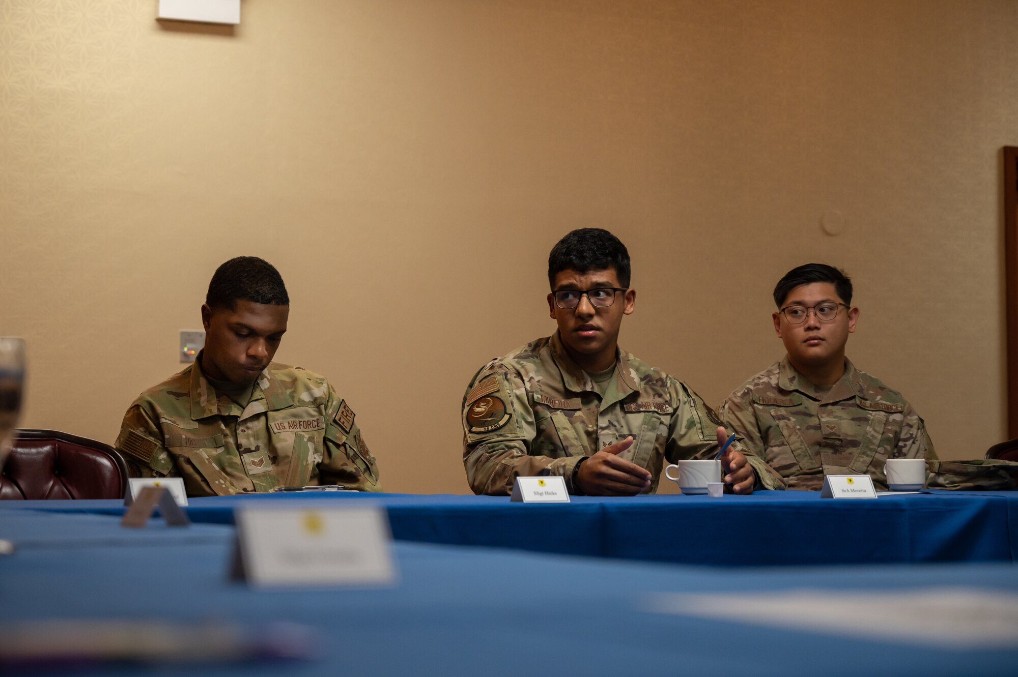 Three Airmen sitting in a discussion group, one is speaking.