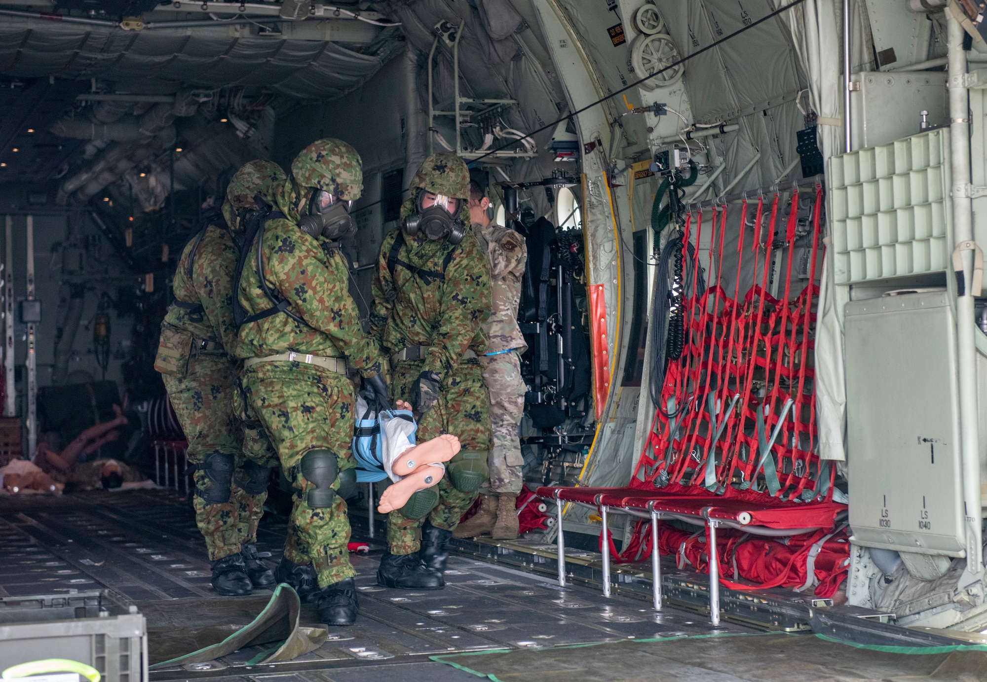 Japan Ground Self-Defense Force Central Biological Chemical Weapons Defense Unit soldiers transport a mock contaminated victim off a C-130J Super Hercules