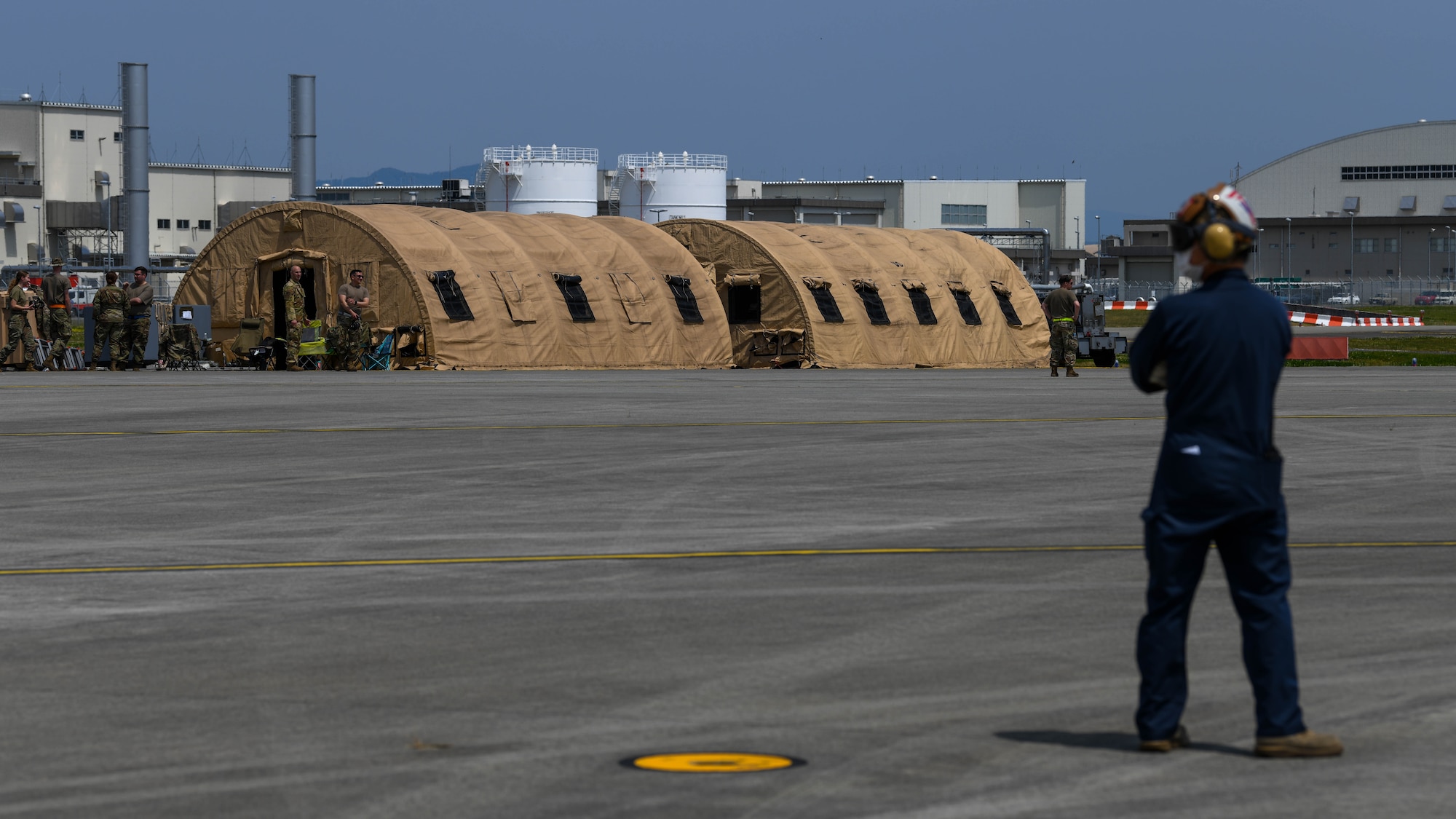Airmen assigned to Yokota Air Base stand next to two forward operating base tents on a flightline at Marine Corps Air Station Iwakuni, Japan, April 19, 2022. FOB tactical planning proficiency was part of the agile combat employment training objectives for this training event. (U.S. Air Force photo by Staff Sgt. Jessica Avallone)