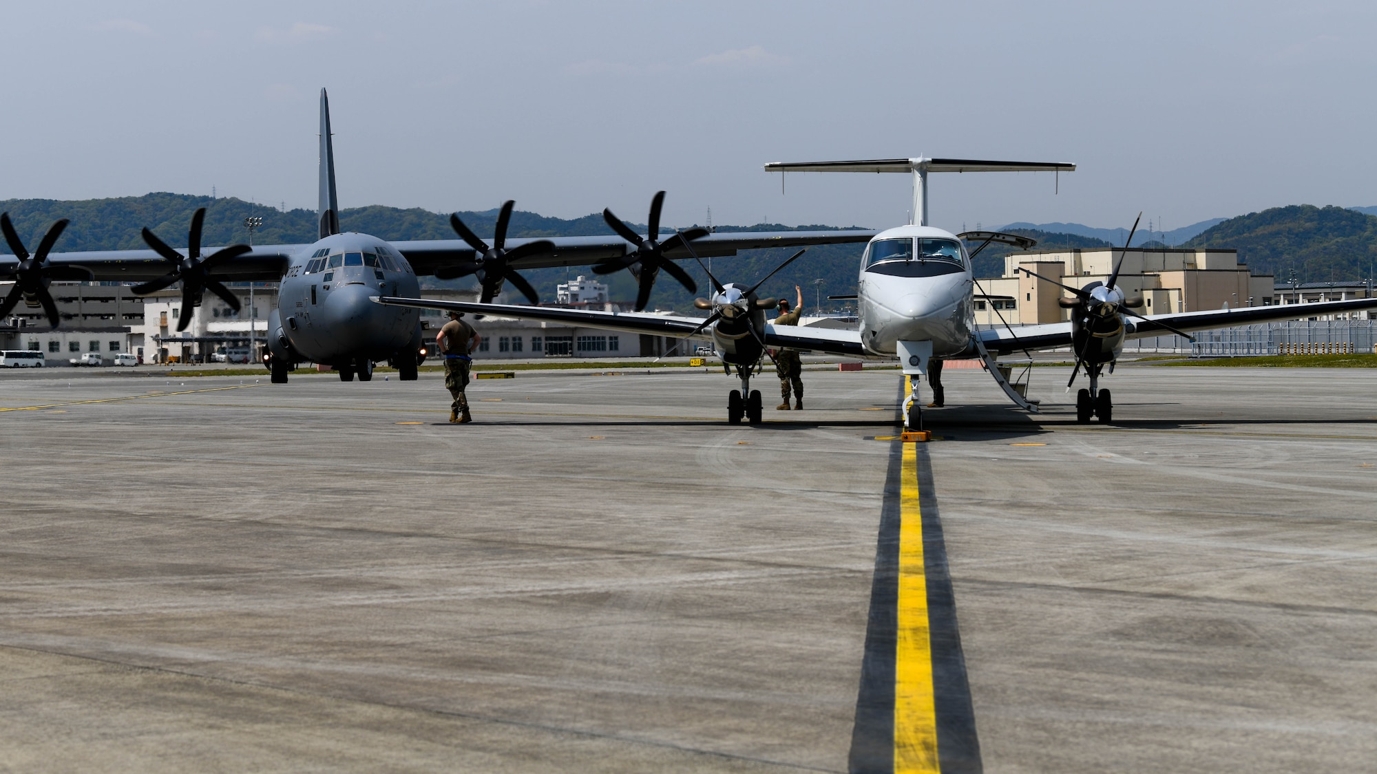 A U.S. Air Force C-130J Super Hercules assigned to the 36th Airlift Squadron taxis next to a U.S. Air Force C-12 Huron assigned to the 459th Airlift Squadron at Marine Corps Air Station Iwakuni, Japan, April 19, 2022. Two C-130Js, one C-12 and one UH-1N Iroquois helicopter assigned to the 459th Airlift Squadron flew to Iwakuni for the training opportunity. (U.S. Air Force photo by Staff Sgt. Jessica Avallone)