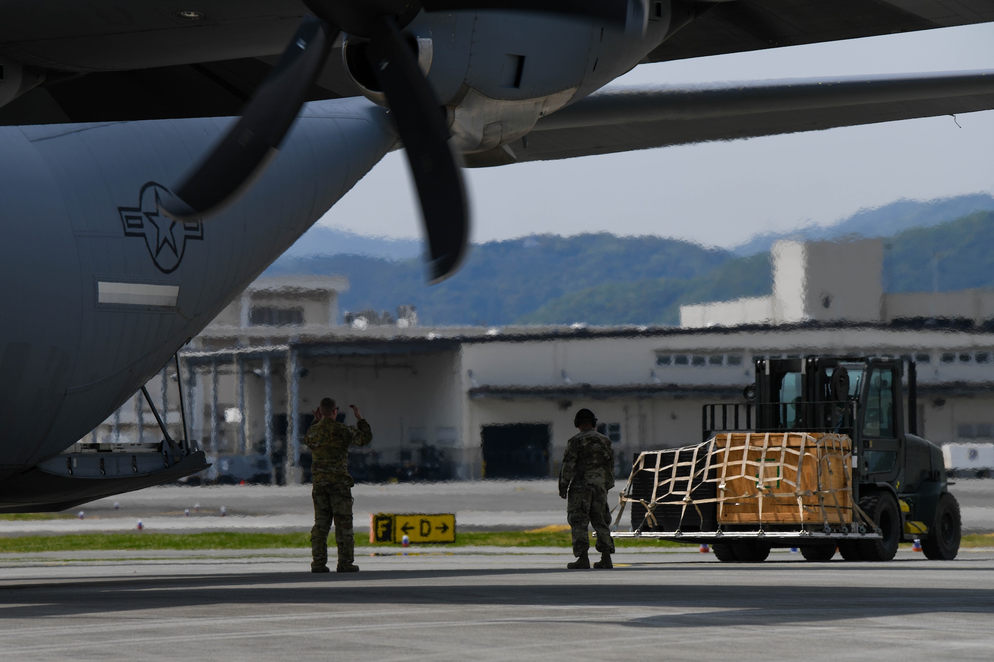 Airmen assigned to Yokota Air Base prepare to load a pallet on to a U.S. Air Force C-130J Super Hercules assigned to the 36th Airlift Squadron at Marine Corps Air Station Iwakuni, Japan, April 19, 2022. Forward operating base tactical execution proficiency was part of the agile combat employment training objectives for this training event. (U.S. Air Force photo by Staff Sgt. Jessica Avallone)
