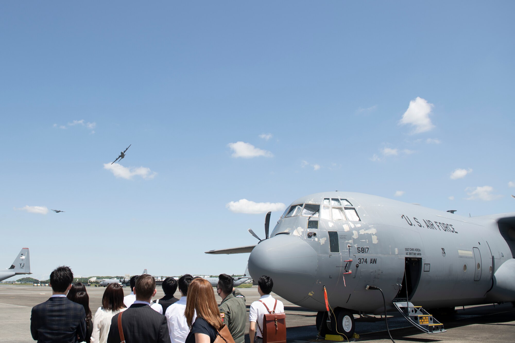 An Ambassador’s Youth Council tour watches as two C-130J Super Hercules flyby during an AYC tour at Yokota Air Base, Japan, April 22, 2022. The tour included a brief on C-130Js and how they support airlift operations within Japan as well as other locations within the Indo-Pacific. (U.S. Air Force photo by Tech. Sgt. Joshua Edwards)