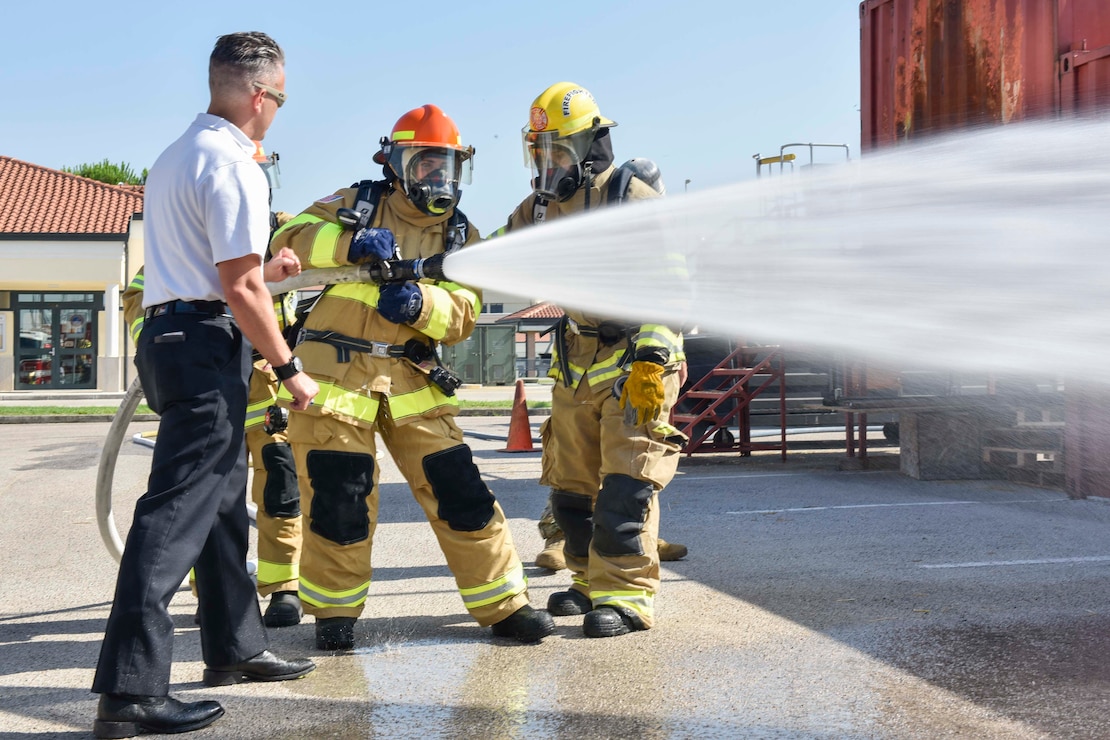 Kate Necaise, center, a member of the Commander, Navy Region Europe, Africa, Central Public Affairs Office, receives firefighting training during a live fire training exercise on board Naval Support Activity (NSA) Naples’ Support Site, June 26, 2020.