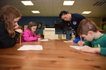 Angelica Williams, 86th Force Support Squadron Airman and Family Readiness Center community readiness consultant, helps students with a money management goal sheet during the “Youth Saves Event,” at Ramstein Air Base, Germany, Feb. 25, 2019. Williams said as the children wrote down their short and long term goals she emphasized with them that no matter how they use their money they should always have a goal with it. The “Youth Saves Event” educates the younger generation on how to build their financial foundation. (U.S. Air Force photo by Senior Airman Kristof J. Rixmann)